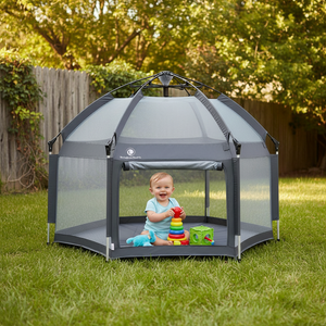 Child playing inside a portable playpen in a backyard